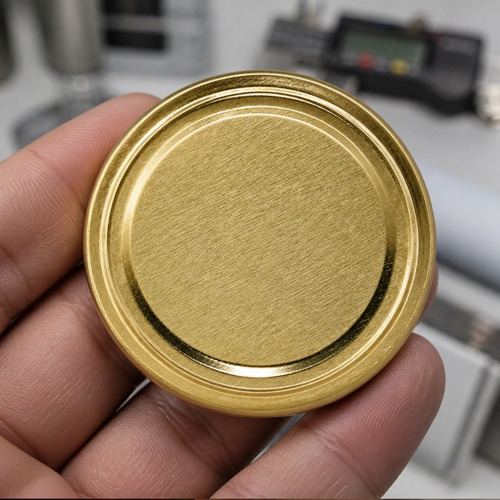 Detailní záběr zlatého víčka na zavařovací sklenice TO63 o průměru 63 mm BasicSeal UniTwist v mužské ruce