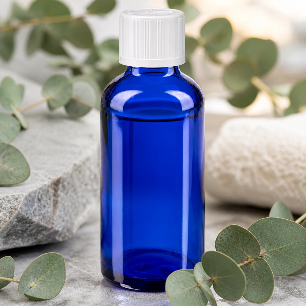 50ml blaue Apoglasflasche mit Tropfeinsatz auf grauem Stein im minimalistischen Spa-Arrangement
