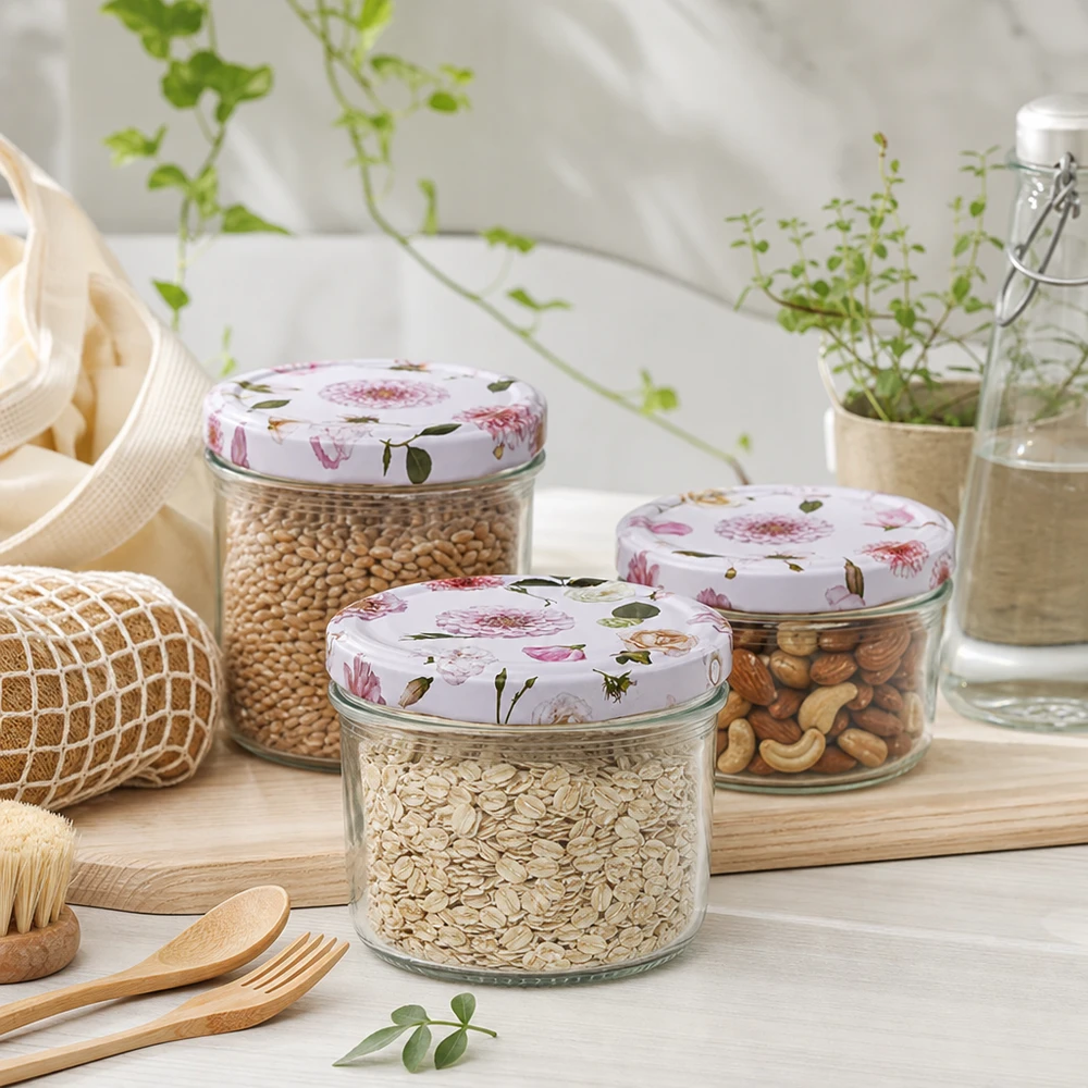 Drei 230ml Zylindergläser mit rosa Blumendeckel gefüllt mit Getreide und Nüssen in nachhaltiger Küchenumgebung