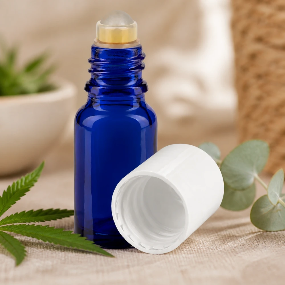 Lékárenská lahvička modrá 10ml roll-on uzávěr bílý Kompakte blaue Apothekerglasfl asche mit Rollapplikator zwischen frischen grünen Pflanzenblättern