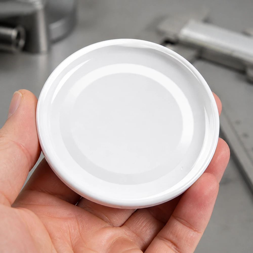 Detailní záběr bílého víčka TO43 o průměru 43 mm BasicSeal UniTwist kulatého tvaru na dlani