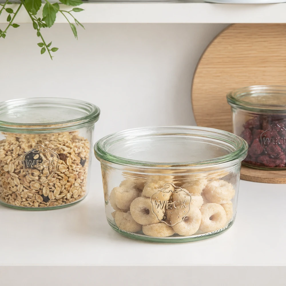 165ml tumble nádoba WECK RR80 se silikonovým silikonem. WECK Sturzglas 165ml RR80 mit Donuts gefüllt neben anderen Vorratsgläsern mit Müsli und Nüssen in weißer Küche
