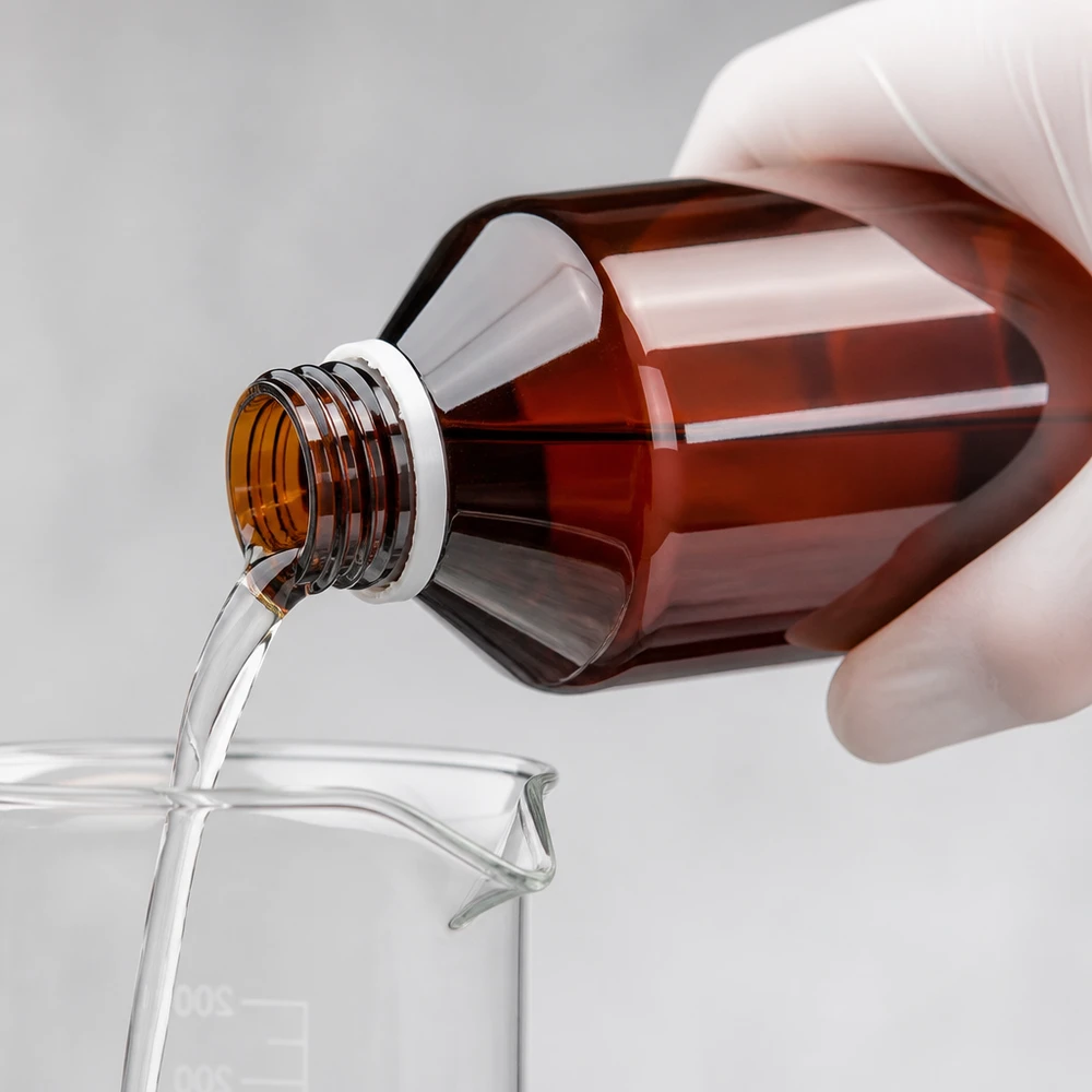 Čirá tekutina se nalévá z hnědé 500ml PET láhve do kádinky s bílým uzávěrem typu OV