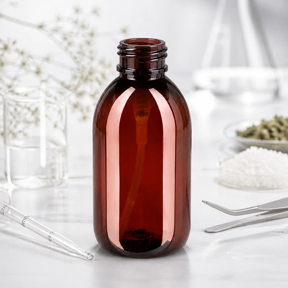 PET láhev 250ml s dávkovací pumpičkou černá Prázdná 250ml PET láhev jantarově hnědé barvy bez uzávěru na bílé laboratorní desce s laboratorními potřebami