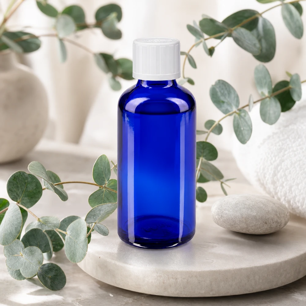 Lékárenská láhev modrá 50ml šroubovací uzávěr bílý standardní odolný proti otevření dětmi. Apothekerglasflasche 50ml kobaltblau mit weißem Verschluss umgeben von Eukalyptuszweigen