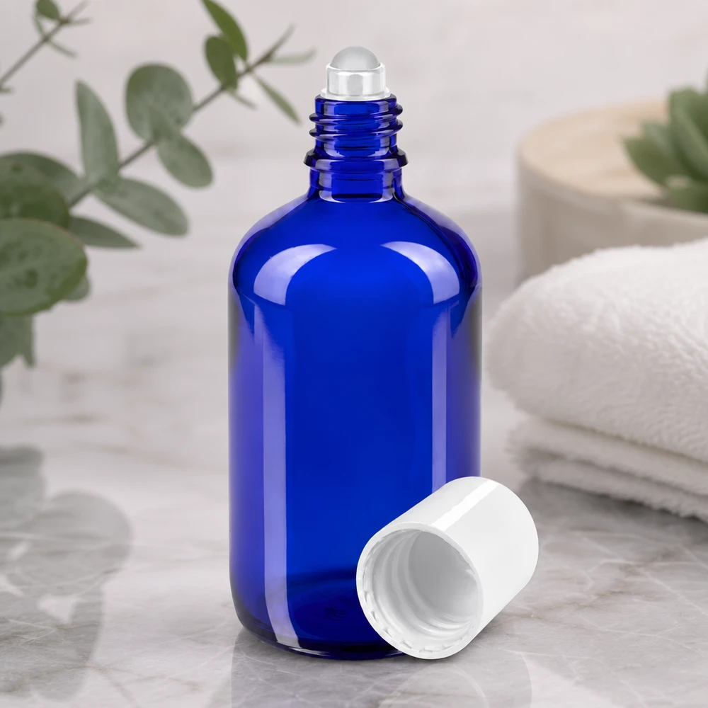 Hochwertige kobaltblaue 100ml Roll-On Flasche aus Apothekerglas vor natürlichem Eukalyptus Hintergrund