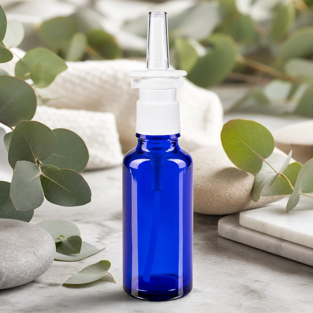 Blaue Apothekerglasflasche 30ml mit Nasenspraykopf umgeben von frischen Eukalyptusblättern