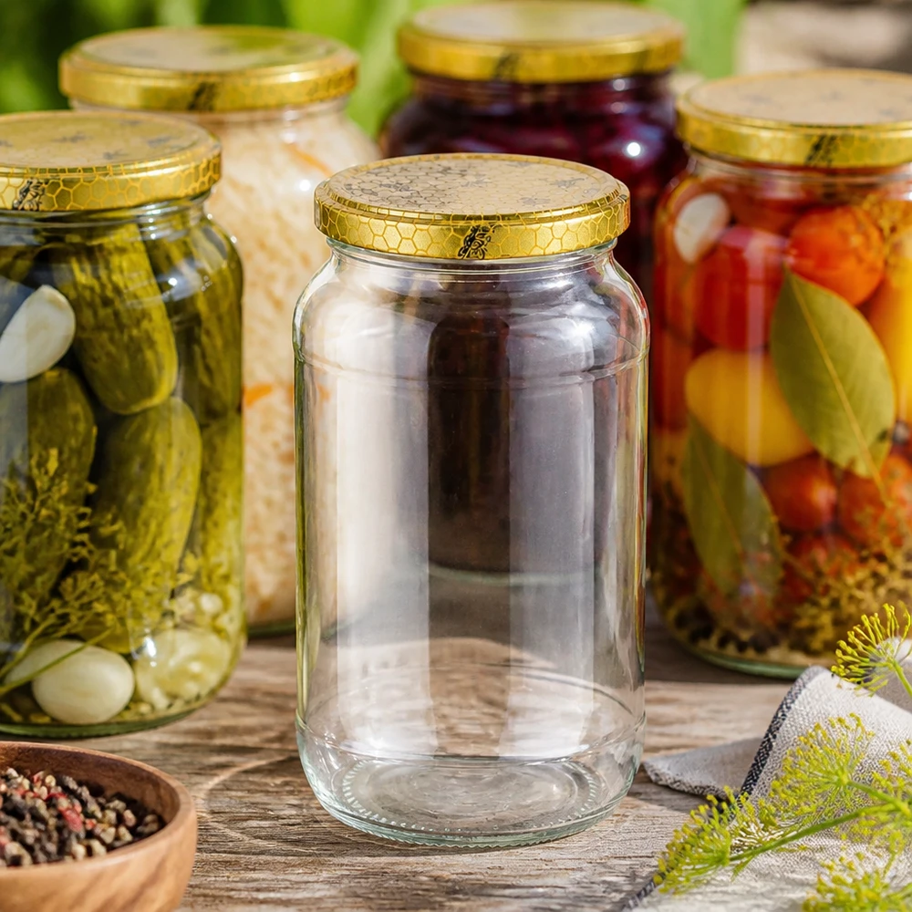 1062ml kulatá sklenice + víčko BasicSeal voština UNiTWIST 1062ml Rundglas leer zwischen gefüllten Einmachgläsern mit Gurken Gemüse goldener Bienenwabe-Deckel Einmachen Konservier