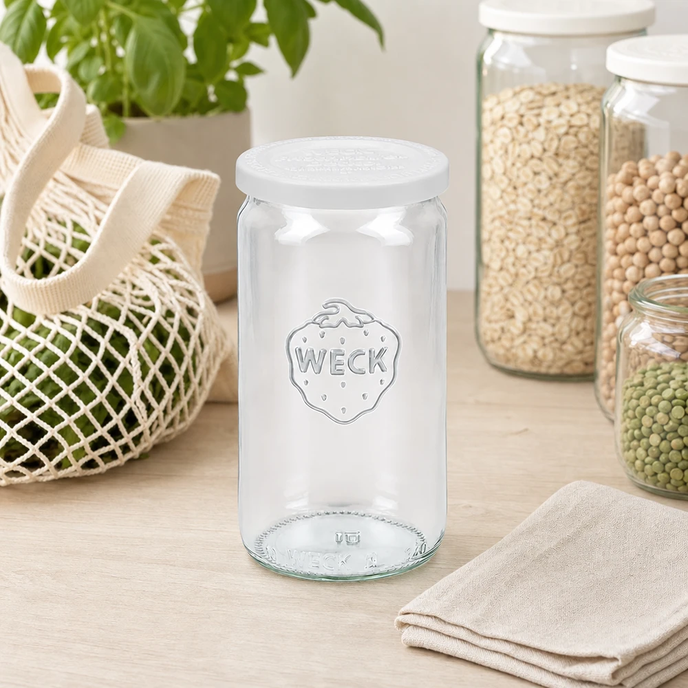 340ml válcová sklenice se skleněným víčkem WECK RR60 pro zachování čerstvosti. WECK Zylinderglas 340ml leer mit RR60 Frischedeckel in skandinavischer Küche zwischen Vorratsgläsern und Netzbeutel