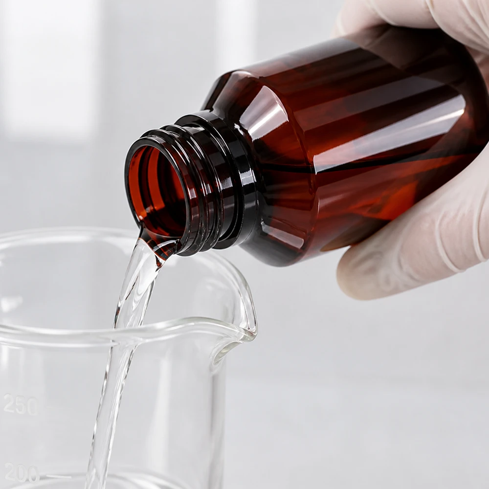 Chemikalienbeständige PET Flasche 100ml bernsteinfarben mit weisser Dispenserpumpe in Laborumgebung