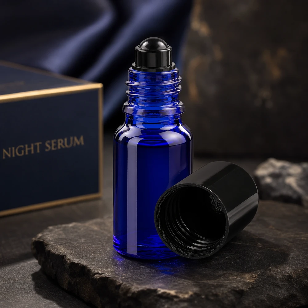 Lékárenská lahvička modrá 10ml roll-on černá uzávěr Geöffnete kobaltblaue 10ml Glasroller Flasche mit schwarzem Schraubverschluss auf dunklem Steinhintergrund
