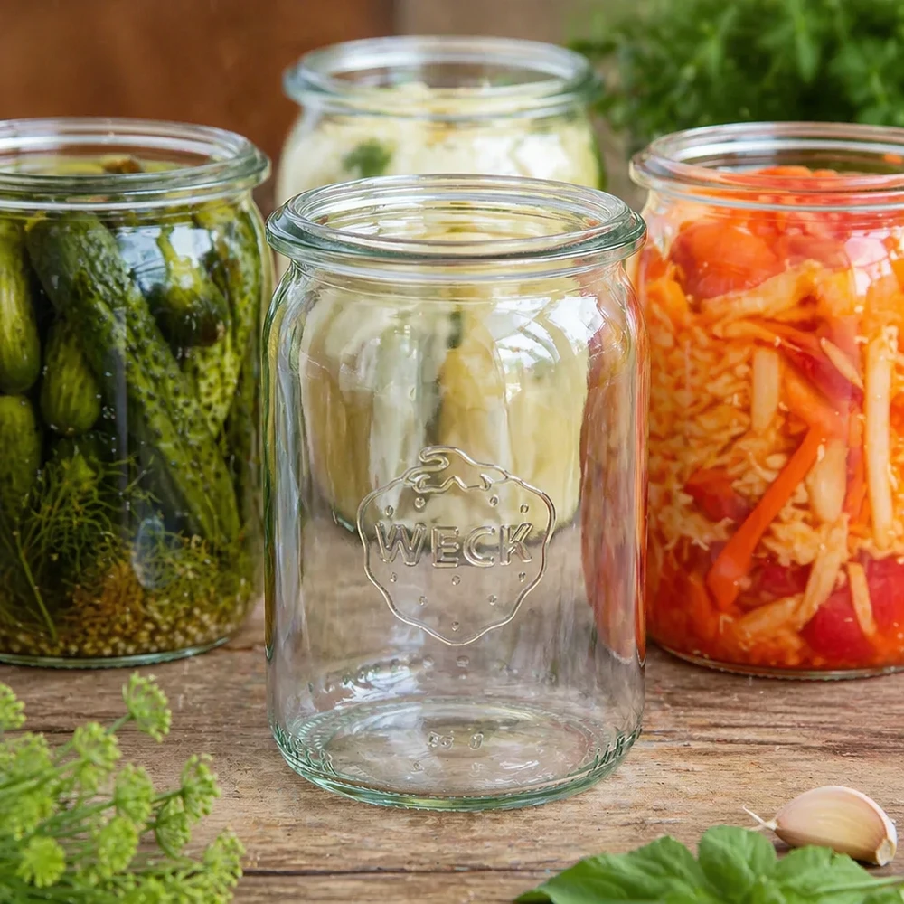145ml válcová sklenice WECK RR40 s dřevěným dřívkem. WECK Zylinderglas 145ml RR40 leer zwischen gefüllten Einmachgläsern mit eingelegtem Gemüse und Fermentation auf Holztisc
