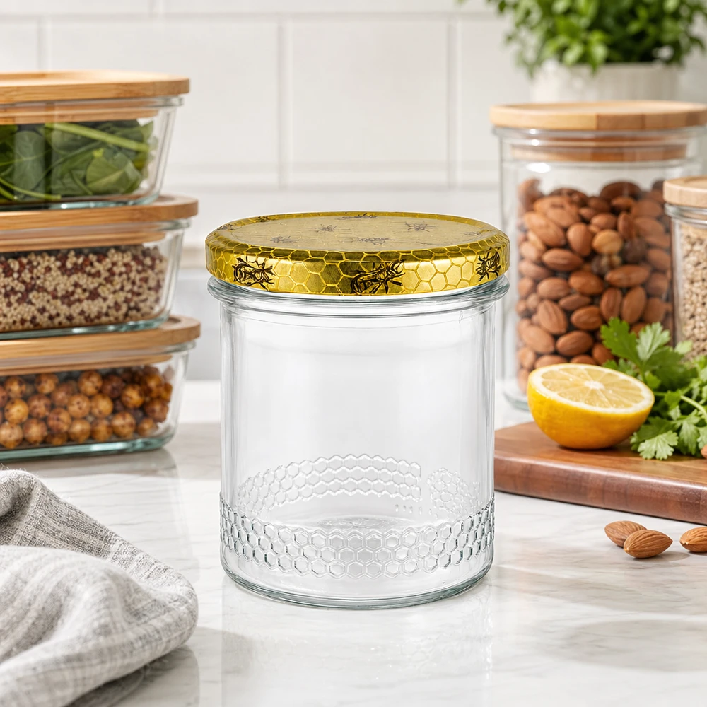 400ml Honigglas mit goldenem Bienenwaben-Deckel auf Küchenarbeitsplatte, Vorratsgläser mit Nüssen im Hintergrund